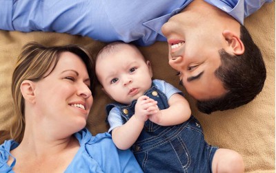 baby-boy-with-parents-at-bed