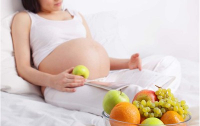 pregnant-at-bed-eating-fruits
